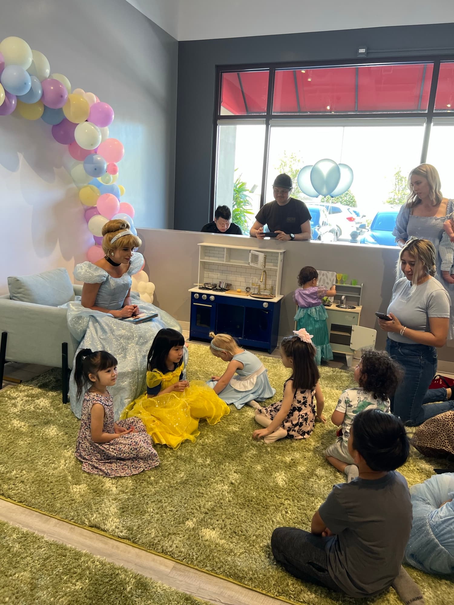 Des enfants assis sur le tapis pendant une lecture de conte par une princesse