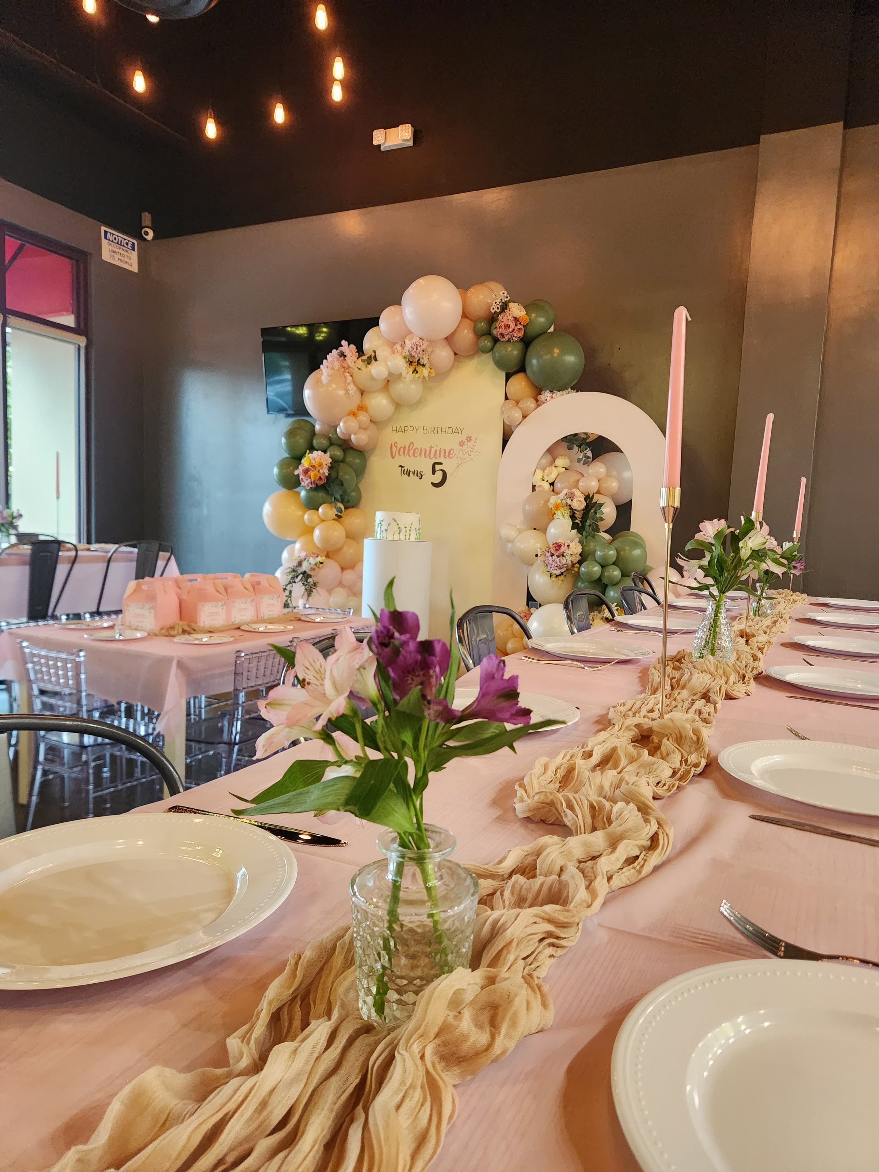 Table de premier anniversaire rose et pêche avec fleurs et arche de ballons chez My Little Paris à San Gabriel