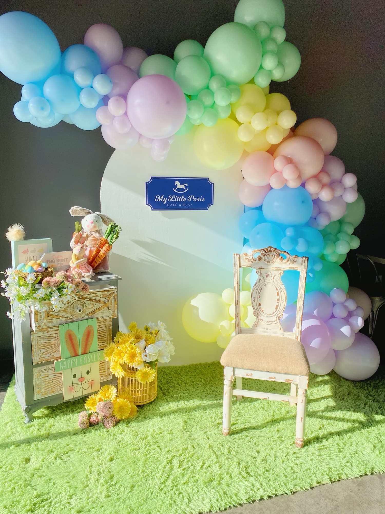 Des ballons arc-en-ciel autour d’une chaise haute pour un premier anniversaire