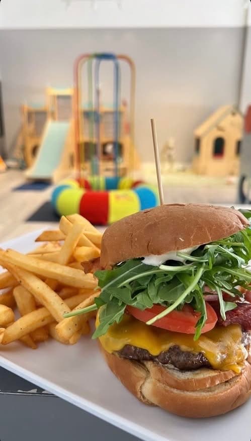 Cheeseburger and fries served beside the softly blurred indoor playground