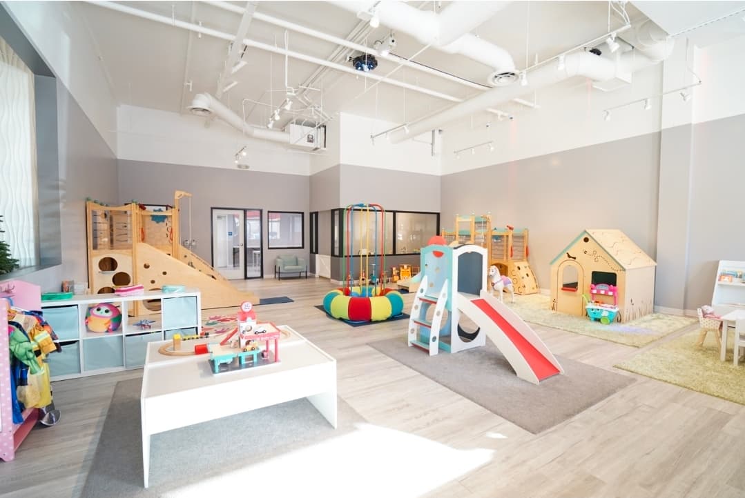 Corner-to-corner view of the bright My Little Paris indoor playground with wooden slides and imaginative play stations