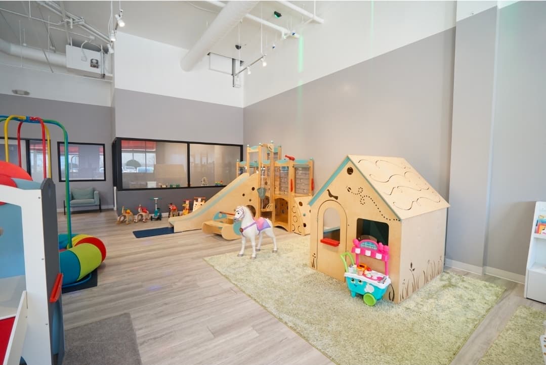 Wooden playhouse and colorful pretend kitchen area inside the children’s indoor playground