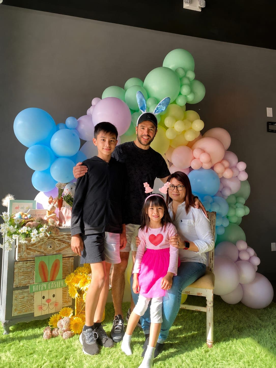 The My Little Paris family celebrating together beneath a pastel balloon arch