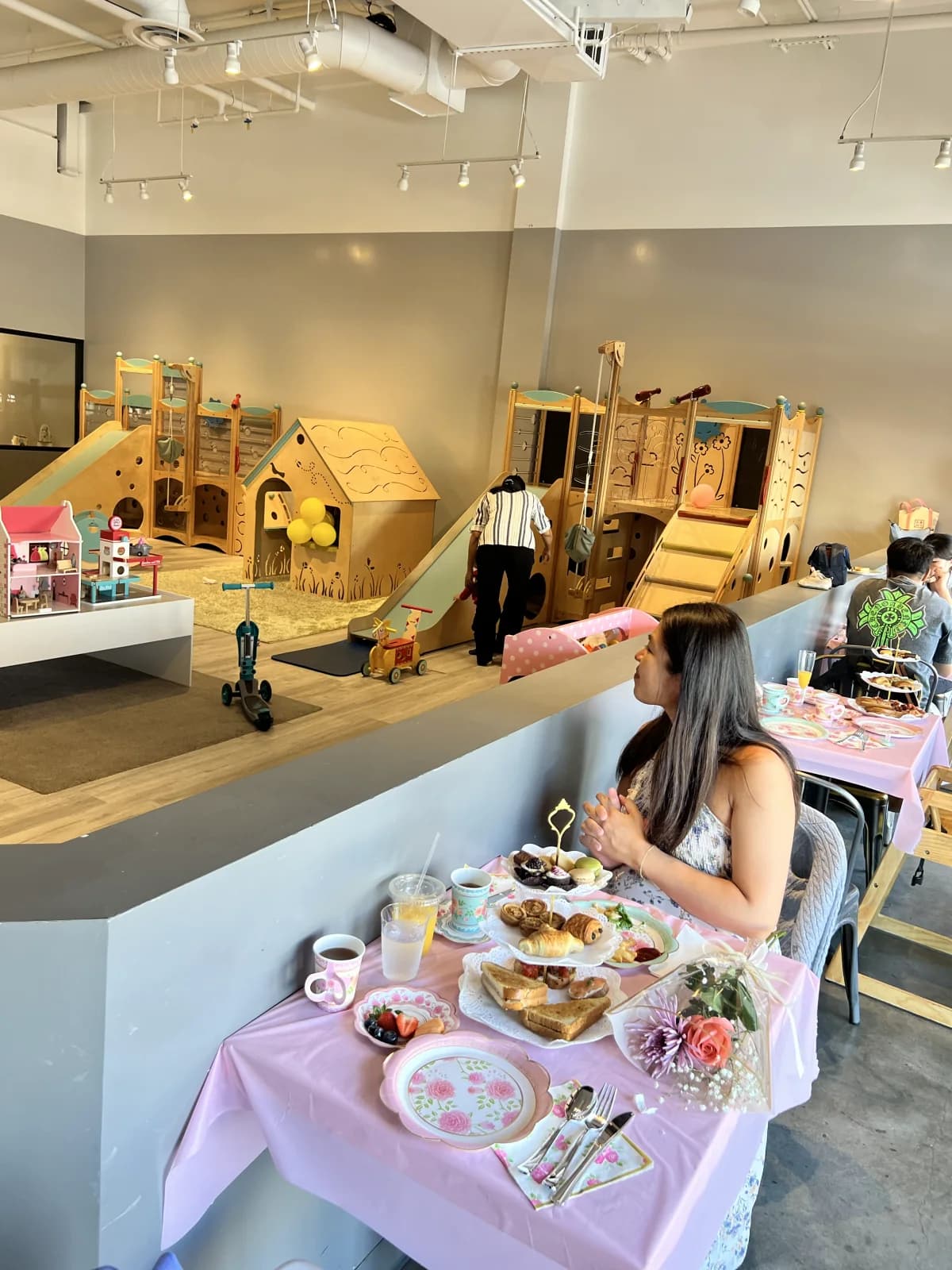 A guest enjoying afternoon tea beside the indoor playground at My Little Paris